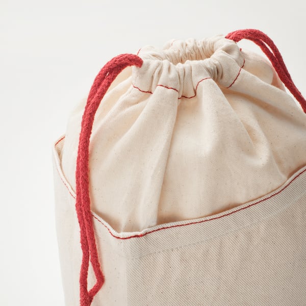 Un sac de rangement en coton de haute qualité avec des cordons de serrage rouges, des coutures soigneusement fermées et détaillées.