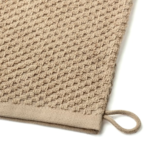 Gros plan sur un gant de lavage en coton doux et texturé. Lavable en machine, avec une boucle suspendue.