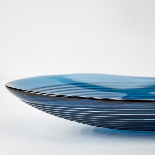Bol en verre bleu, design lisse et fluide, ondulations délicates.