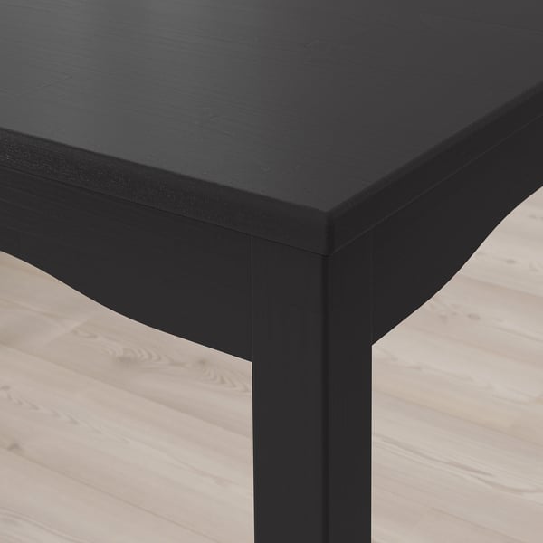 Gros plan d’une table en bois noir élégante et moderne avec une finition lisse et des bords robustes.