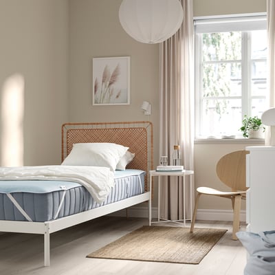 Chambre calme avec lit simple, protecteur de refroidissement bleu HÅRGINST, cadre blanc, chaise en bois, table d’appoint, tapis, rideau, fenêtre, photo, lampe.