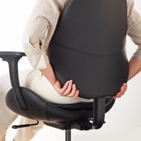 Personne assise sur une chaise ergonomique, ajustant le support dorsal.