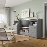 Salon moderne avec séquence HAUGA : meubles de rangement gris, télévision à écran plat, décoration carte du monde, parquet et murs végétaux.