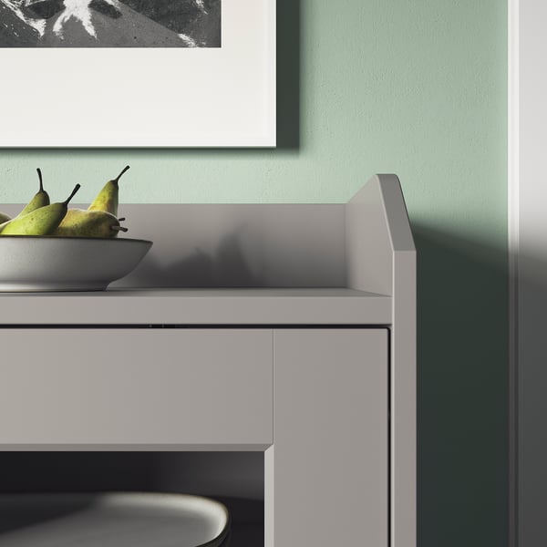 Armoire blanche avec portes vitrées, exposant des fruits dans un bol, adossée à un mur végétal. Design moderne et épuré.