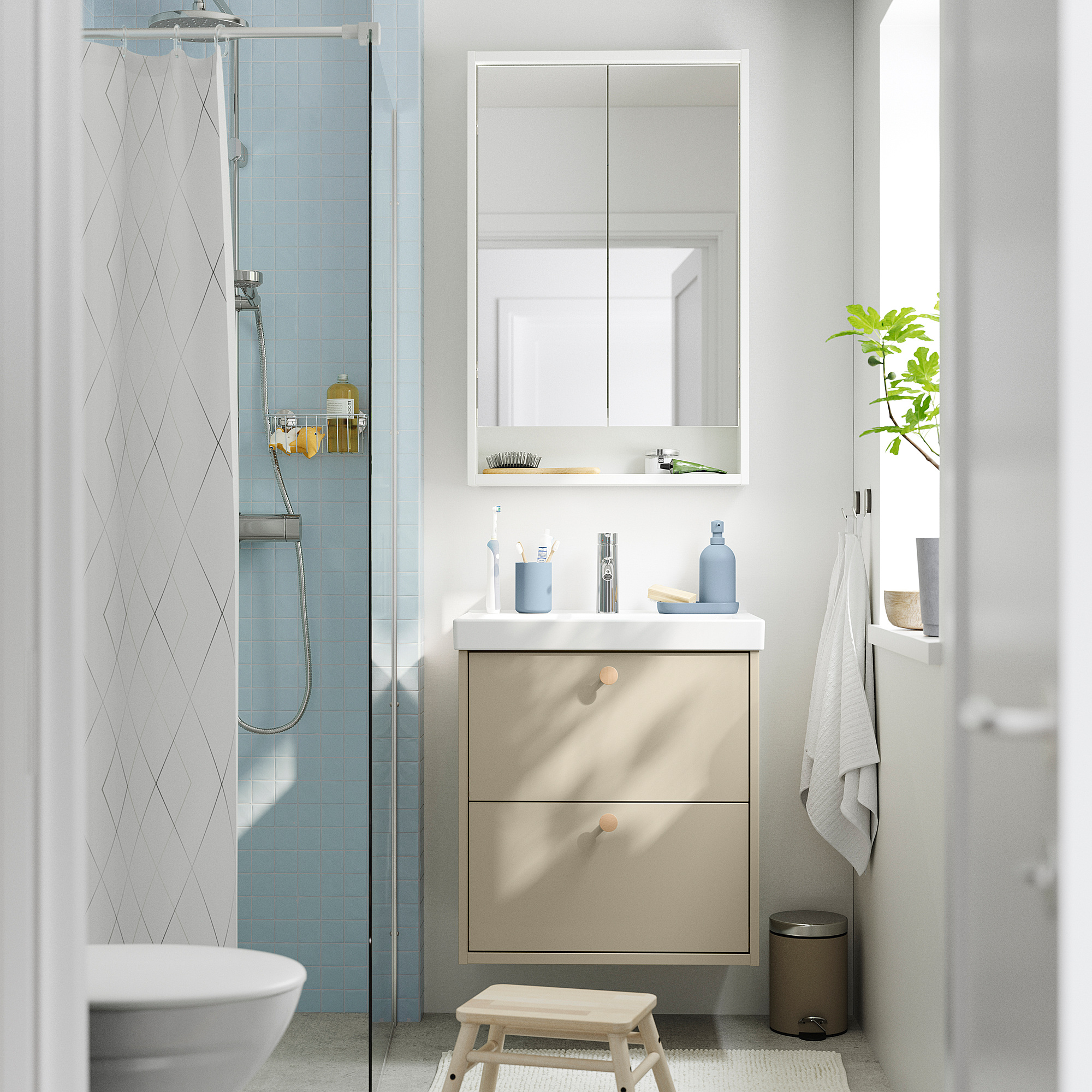 Salle de bain moderne avec meuble-lavabo beige HAVBÄCK, carrelage bleu clair, lavabo blanc, douche en verre et petite plante.