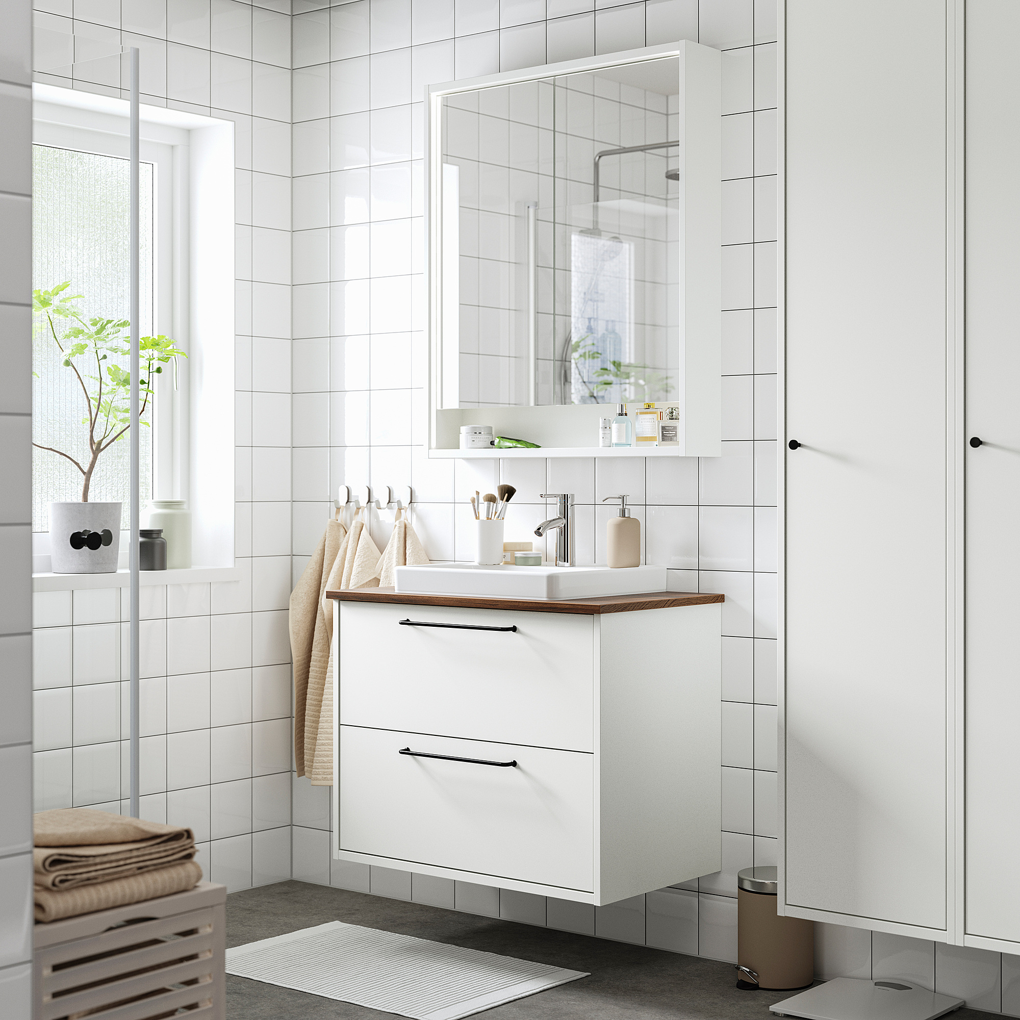 Armoire de salle de bain blanche minimaliste avec comptoir et miroir, poignées en bois, serviettes, plante.