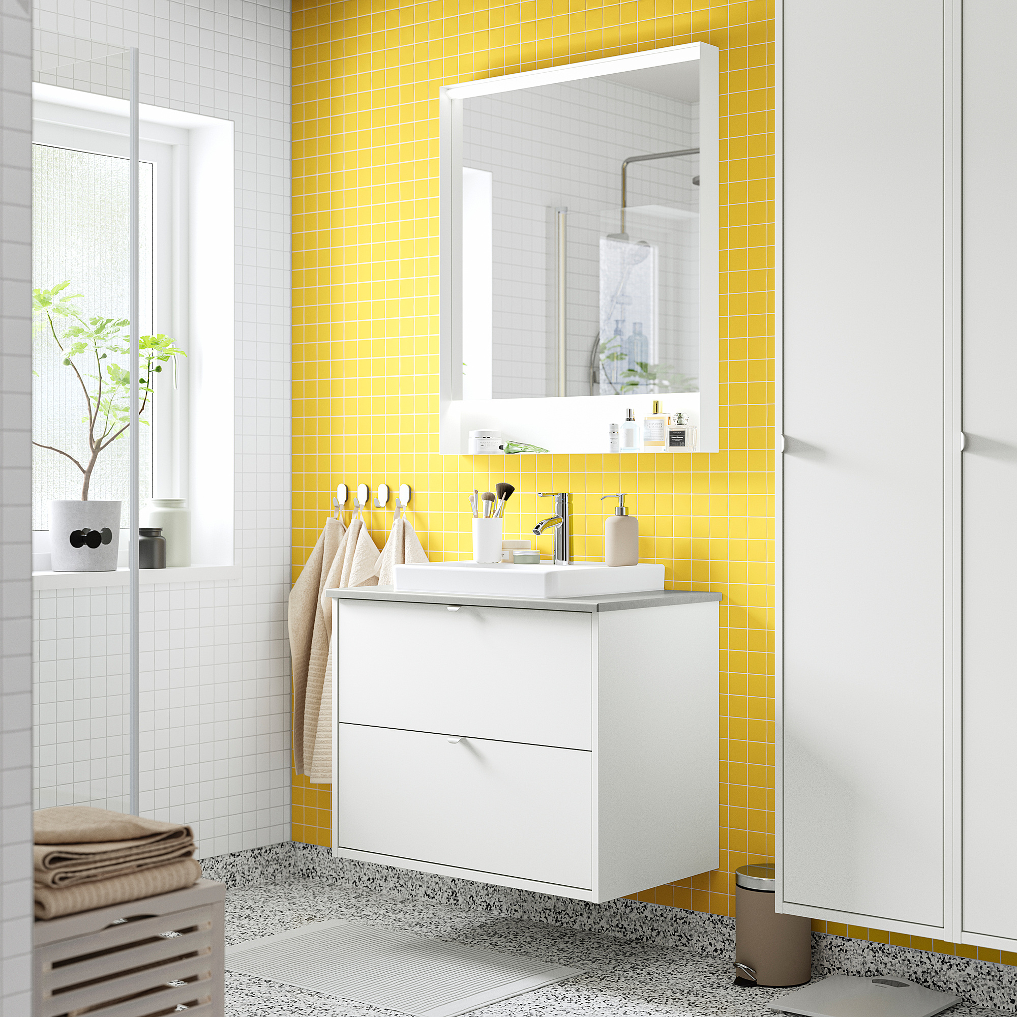 Salle de bains carrelée jaune vif avec meuble-lavabo, lavabo et armoires HAVBÄCK blancs. Design moderne, mural, avec de nombreux rangements.