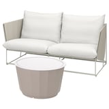 Canapé d’extérieur blanc moderne avec coussins et table basse. Cadre en métal élégant, coussins moelleux, table d’appoint circulaire.
