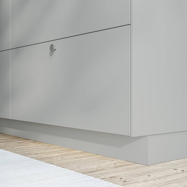Armoire de cuisine blanche au design élégant et sans poignée et parquet en bois clair.