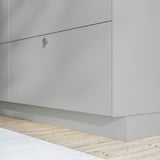 Armoire de cuisine blanche au design élégant et sans poignée et parquet en bois clair.