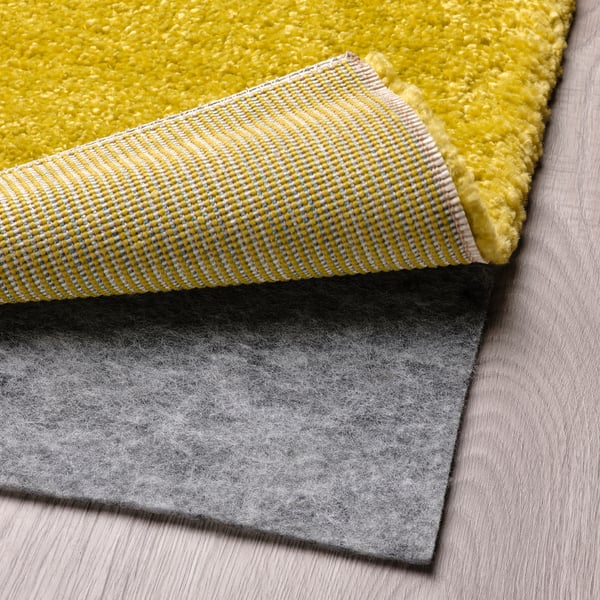 Tapis lumineux avec un motif rayé et une sous-couche de tapis grise, mettant en valeur une fonctionnalité antidérapante.