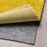 Tapis lumineux avec un motif rayé et une sous-couche de tapis grise, mettant en valeur une fonctionnalité antidérapante.