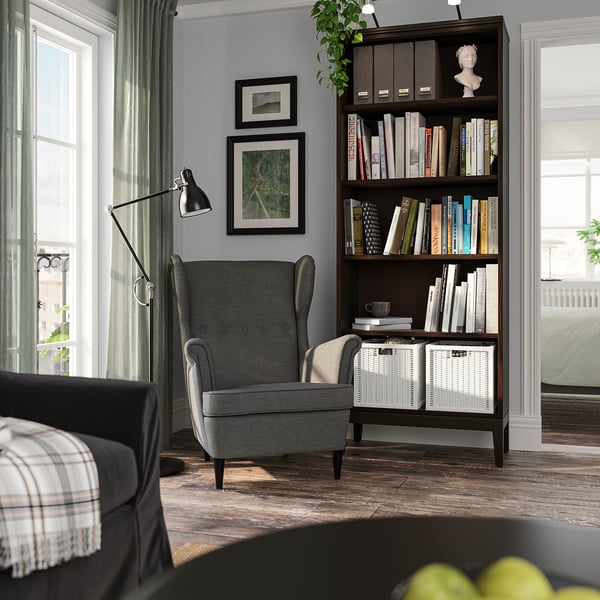 Coin lecture confortable avec étagère IDANÄS grise, chaise noire, lampe et œuvres d’art encadrées sur des murs gris.