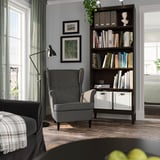 Coin lecture confortable avec étagère IDANÄS grise, chaise noire, lampe et œuvres d’art encadrées sur des murs gris.