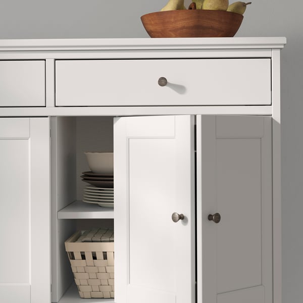 Buffet IDANÄS blanc avec portes pliées, une assiette ouverte révélatrice et un panier.