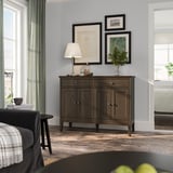 Chambre moderne : buffet IDANÄS avec portes pliantes et cadres d’art décoratifs. Éclairage tamisé, bois sombre, décor calme.