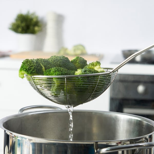 Écumoire soulevant le brocoli, le liquide s’écoule.