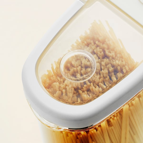 Récipient en plastique transparent avec deux compartiments remplis de pâtes, empilés l’un sur l’autre.