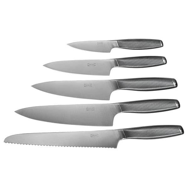 Six couteaux IKEA 365+, en acier inoxydable avec des poignées rainurées noires, disposés soigneusement en rangée, adaptés à diverses tâches de cuisine.