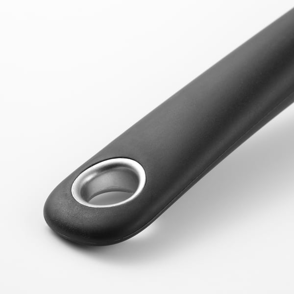 Ustensile de cuisine noir avec poignée en silicone et anneau métallique, conçu pour une manipulation confortable et sûre.