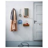 Entrée bien rangée avec manteau, écouteurs, horloge, miroir, pommes près de la porte.