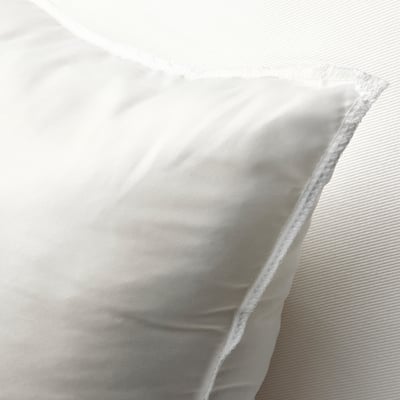 Un gros plan d’un coussin blanc moelleux, mettant en valeur son tissu doux et texturé et son design dodu et invitant.