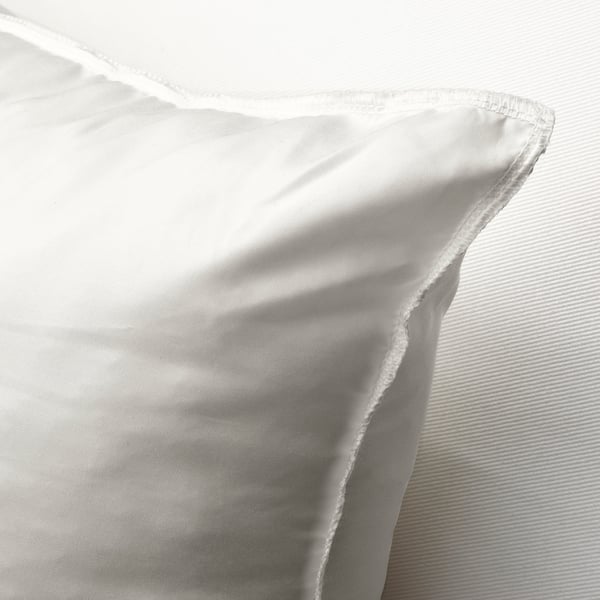 Coussin blanc moelleux avec un tissu lisse et tissé serré, rembourré pour le soutien et le confort, posé sur une surface texturée.
