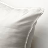Coussin blanc moelleux avec un tissu lisse et tissé serré, rembourré pour le soutien et le confort, posé sur une surface texturée.