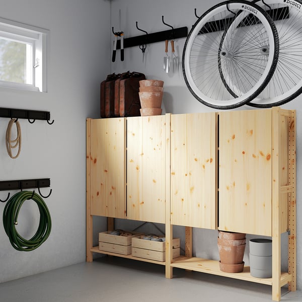 Armoire en bois avec des outils de jardinage, une roue de vélo et des plantes.
