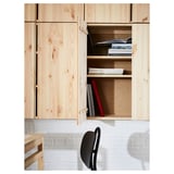 Armoire IVAR en bois de couleur claire stockant des livres, avec une chaise noire devant.