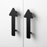 Deux poignées noires modernes et minimalistes en forme de flèche fixées à des portes d’armoires blanches. Finition élégante de haute qualité avec un design robuste.