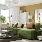 Salon moderne avec canapé vert JÄTTEBO, coussins beiges, murs moutarde et lampes.