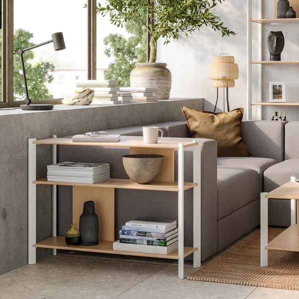 Salon minimaliste avec étagère en bambou JÄTTESTA, canapé gris et grande fenêtre.