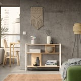 Salon moderne avec murs gris, meubles en bois, canapé vert, étagère, œuvres d’art et chaises en bois.