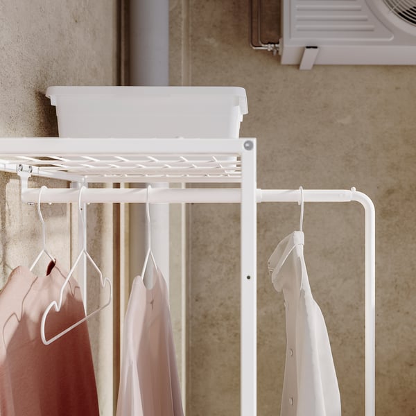 Porte-vêtements JOSTEIN blanc avec étagère, chemises roses suspendues.
