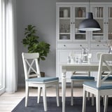 Petite salle à manger confortable avec des coussins de chaise JUSTINA blancs, des coussins gris et un décor moderne.