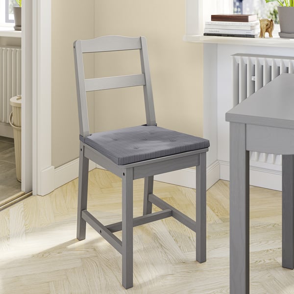 Une chaise en bois gris JUSTINA avec une assise rembourrée.