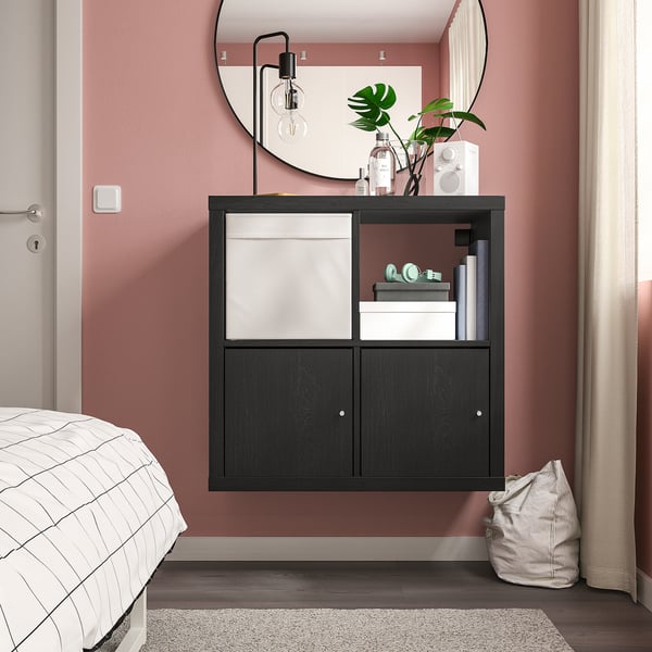 Chambre moderne avec rangement KALLAX noir, livres, décoration, plante, miroir et lit à carreaux.