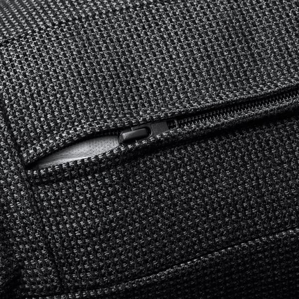 Gros plan d’un tissu texturé de haute qualité sur des meubles modernes avec une élégante tirette de fermeture éclair noire, mettant en valeur un savoir-faire durable.