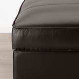 Gros plan du repose-pieds en cuir noir KIVIK, mettant en valeur un cuir lisse et grainé de haute qualité et des coutures soignées.