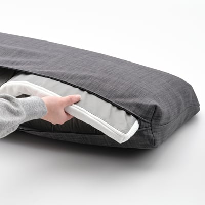 Personne ouvrant coussin de canapé-lit gris.