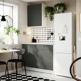 Cuisine moderne : armoires grises, comptoir en marbre, accents noirs, plantes suspendues, sous la fenêtre, grand réfrigérateur.