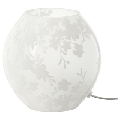 La lampe KNUBBIG, blanche, en verre avec un motif de fleurs de cerisier peint, de forme sphérique, émet une douce lumière d’ambiance.