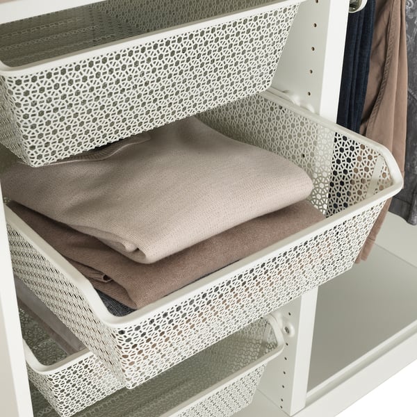 Paniers en métal blanc dans l’armoire stockant les vêtements pliés, permettant la circulation de l’air.