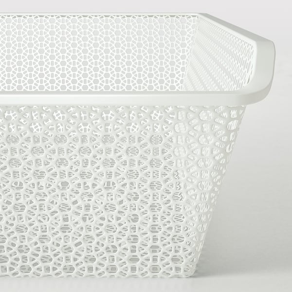 Panier en métal blanc avec des motifs découpés géométriques complexes pour la circulation de l’air et le stockage.