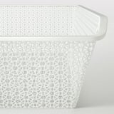 Panier en métal blanc avec des motifs découpés géométriques complexes pour la circulation de l’air et le stockage.
