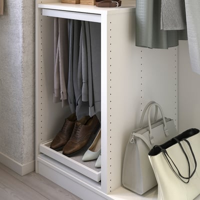 Un organisateur d’armoire ikea KOMPLEMENT blanc, avec un panneau supérieur et inférieur. Il est conçu avec une cloison pour ranger les vêtements efficacement.