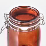 Pot en verre transparent avec couvercle teinté marron, fermoir métallique, doublure en caoutchouc scellée.