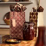 Sacs-cadeaux réutilisables avec mouchoir, étiquette, assiette de granola, pot sur la table.