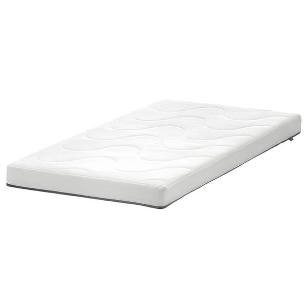 Un matelas de lit bébé blanc et rectangulaire KRUMMELUR d’ikea, doté d’un côté ondulé pour un confort mi-ferme et d’un côté lisse pour un soutien plus ferme.